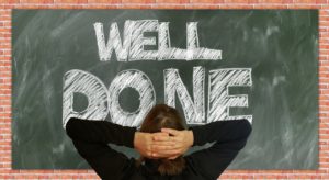 The chalk board illustrating well done, with a student in front of it.