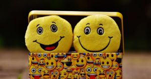 Two stuffed happy faces in a basket.