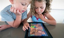 The picture of two little kids, playing with their fun learning tablet.