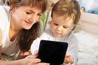 The picture of a mother alongside of hear very young child, still in her toddler years, engaging a fun learning device.