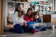 The colorful picture of a Mother and her children engaging there Android tablet.